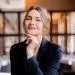 Portrait of smiling successful businesswoman looking into camera sitting in the restaurant. Business lady with stylish hairstyle wears elegant suit. Business meeting. Attractive appearance